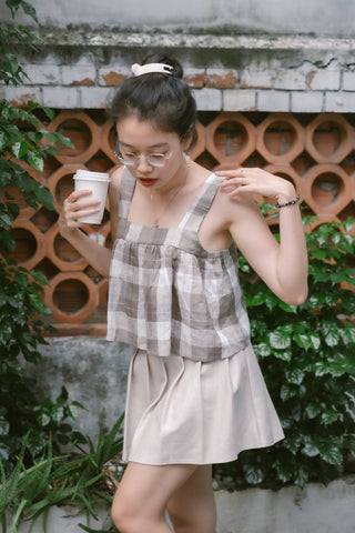 Fille tenant une tasse et portant une mini-jupe beige et un haut sans manches