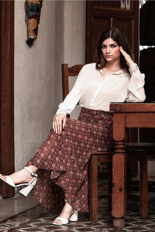 Woman posing with a long patterned skirt and a white transparent shirt