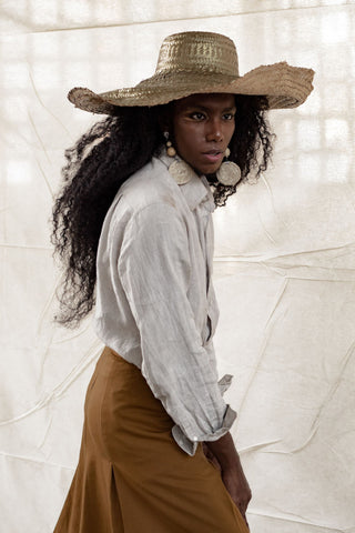 A close shot of black woman with wide brimmed hat and a linen shirt