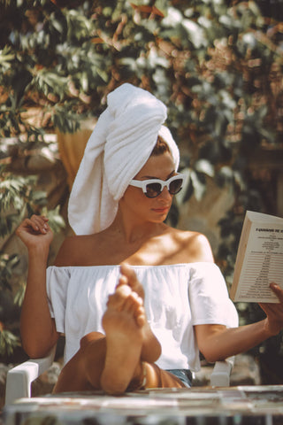 Woman sitting and reading a book wearing a white boat neckline top