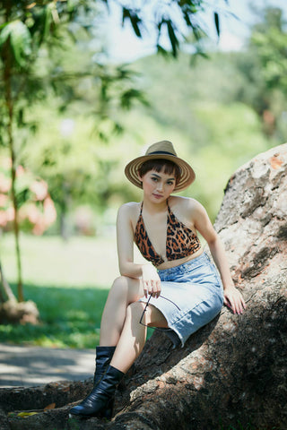Junge Frau posiert sitzend mit Jeansrock und Animalprint-Top