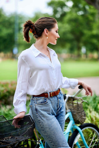 A woman posing in white button-up and jeans
