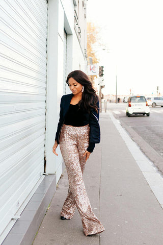 Woman walking wearing sequin bell-bottoms and a black blazer