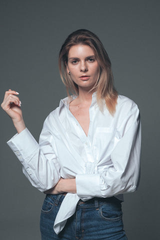 Femme posant pour une photo portant une chemise blanche et un jean