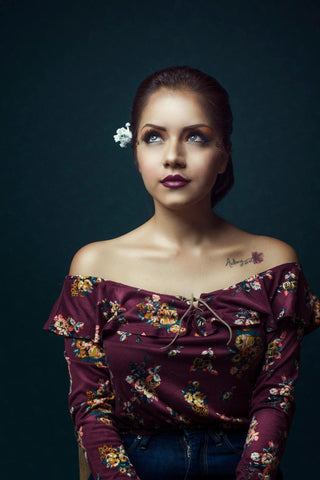 Close photo of a woman posing with an off-the-shoulder floral blouse