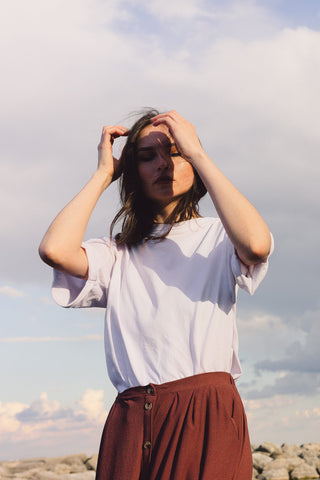 Close photo of a woman posing in white t-shirt and brown skirt