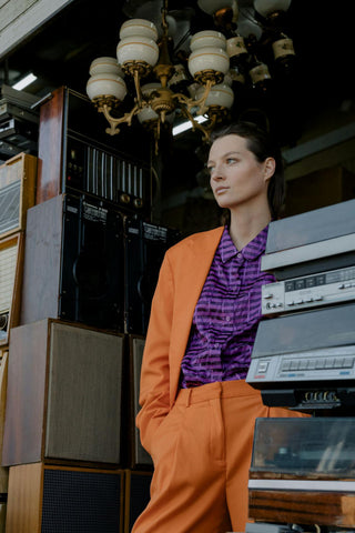 Photo of a woman wearing orange suit with a purple shirt underneath