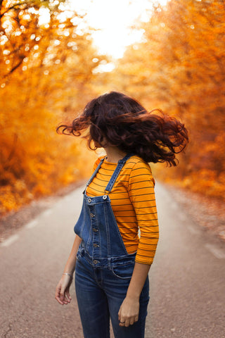 Woman wearing denim dungarees and a yellow blouse