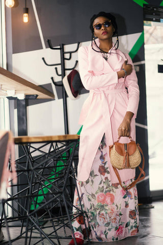 Black woman posing with a floral maxi dress and a pink trench coat