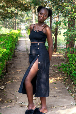 Femme noire posant avec une jupe midi en lin noir et un crop top