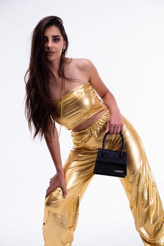 Woman posing in gold faux leather pants and top