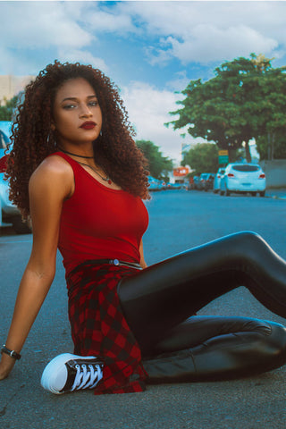 Girl posing on the street with leather leggings, a red tank top, and sneakers
