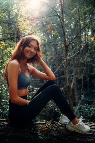 Girl sitting on a tree posing in leggings and a bra top