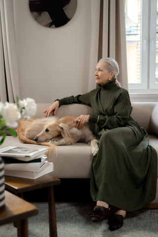 Elderly woman sitting on a sofa with her dog wearing an olive maxi dress