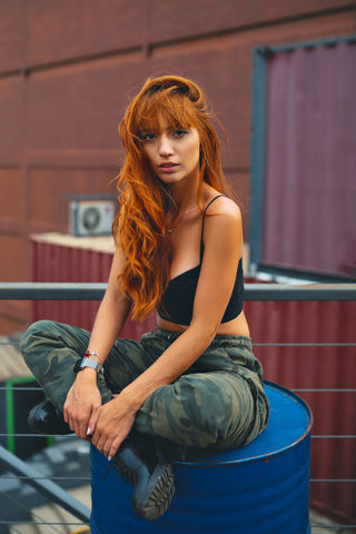 Girl sitting on barrel wearing camouflage military-style pants