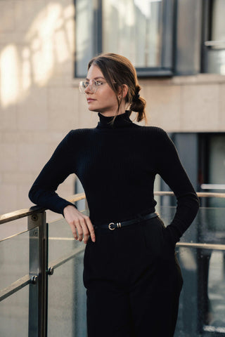 Jeune femme posant avec un col roulé noir et un pantalon