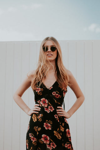 Woman posing with a black floral dress and sunglasses