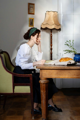 Femme dînant dans un chemisier blanc et une jupe longue noire