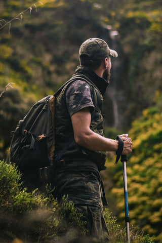 Photo of man in a forest wearing a vest and a tourist backpack