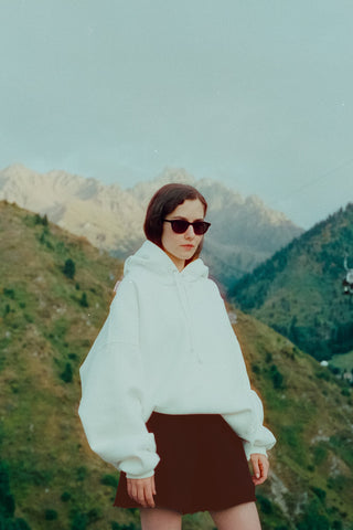 A girl posing in a white hoodie and brown mini skirt