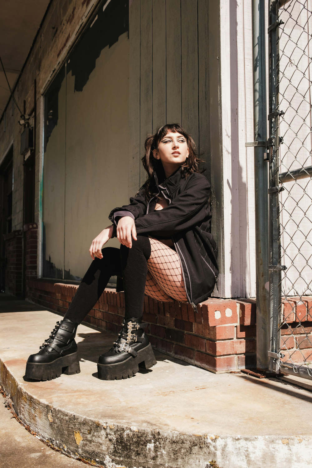 Girl sitting posing with fishnet tights and chunky boots