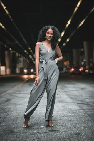 A woman posing in a long grey jumpsuit