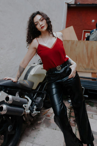 Femme posant avec un haut en satin rouge et un pantalon en cuir noir