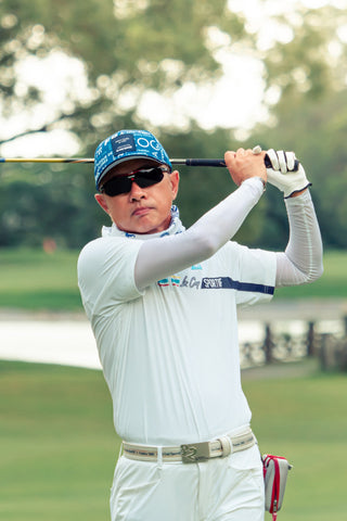 A man playing golf in a white thermal base shirt and a polo shirt on top of it