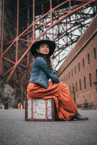 Woman sitting on a suitcase under a bridge