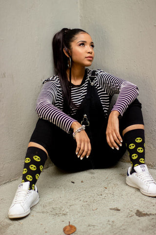A woman wearing black socks with yellow smiley faces on them