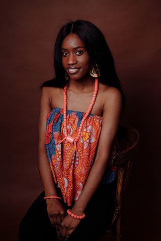 Black woman wearing an off-the-shoulder top and chunky jewelry