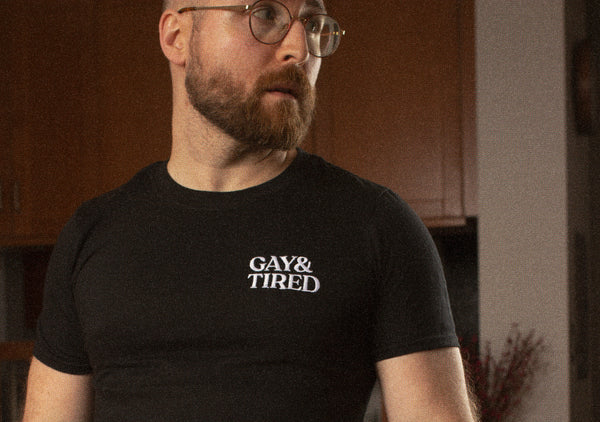 Man wearing a t-shirt that says Gay & Tired embroidered