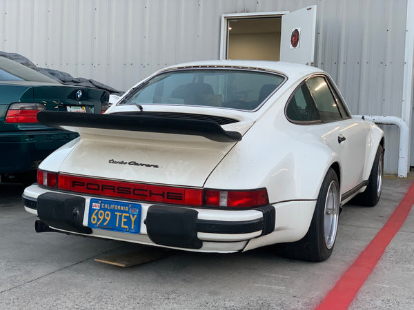 A 1976 Porsche 911 Turbo Carrera Rear Quarter View in the parking space next to the shop