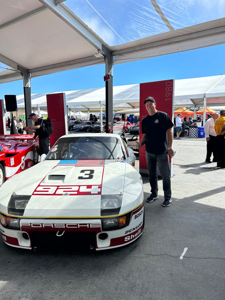 Joe Anselmo standing next to a 1980 Porsche 924 Carrera GTP at Rennsport Reunion 7