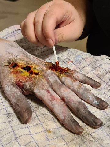 tutorial til zombiehånd, hvor blod smøres ud i de falske sår med en vatpind