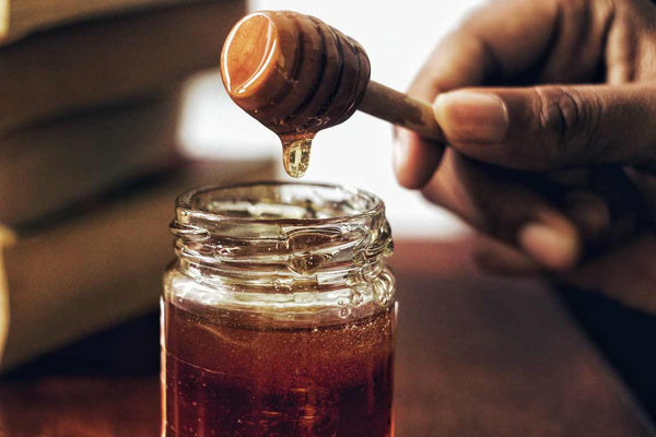 Jar of Rainbow Bees Honey with honey stick. Hawaiian Honey experts that grow Organic raw Hawaiian honey