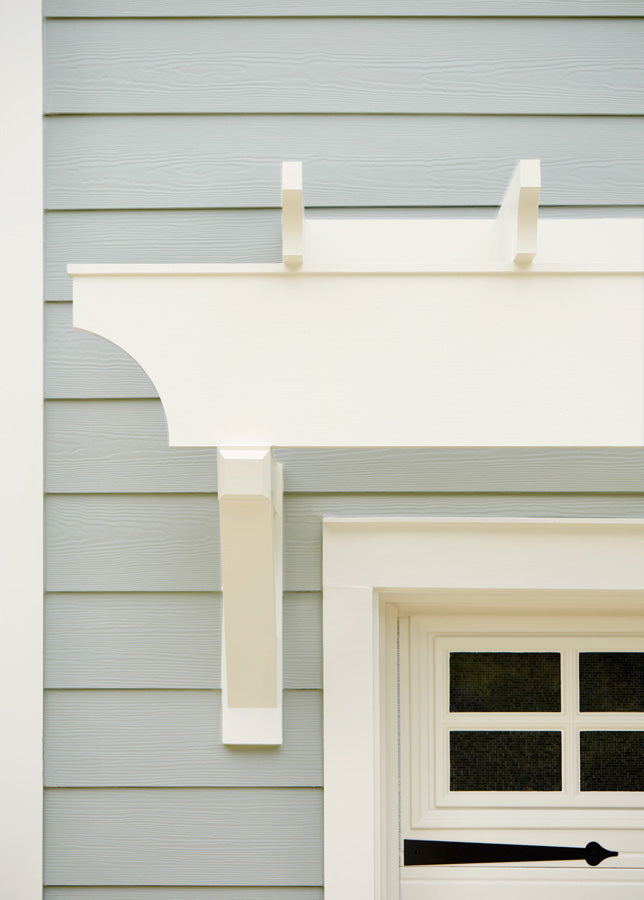 In this close-up detail of the trim and garage door, the siding is painted with Grayish gray exterior paint and the trim is painted in a creamy neutral color.