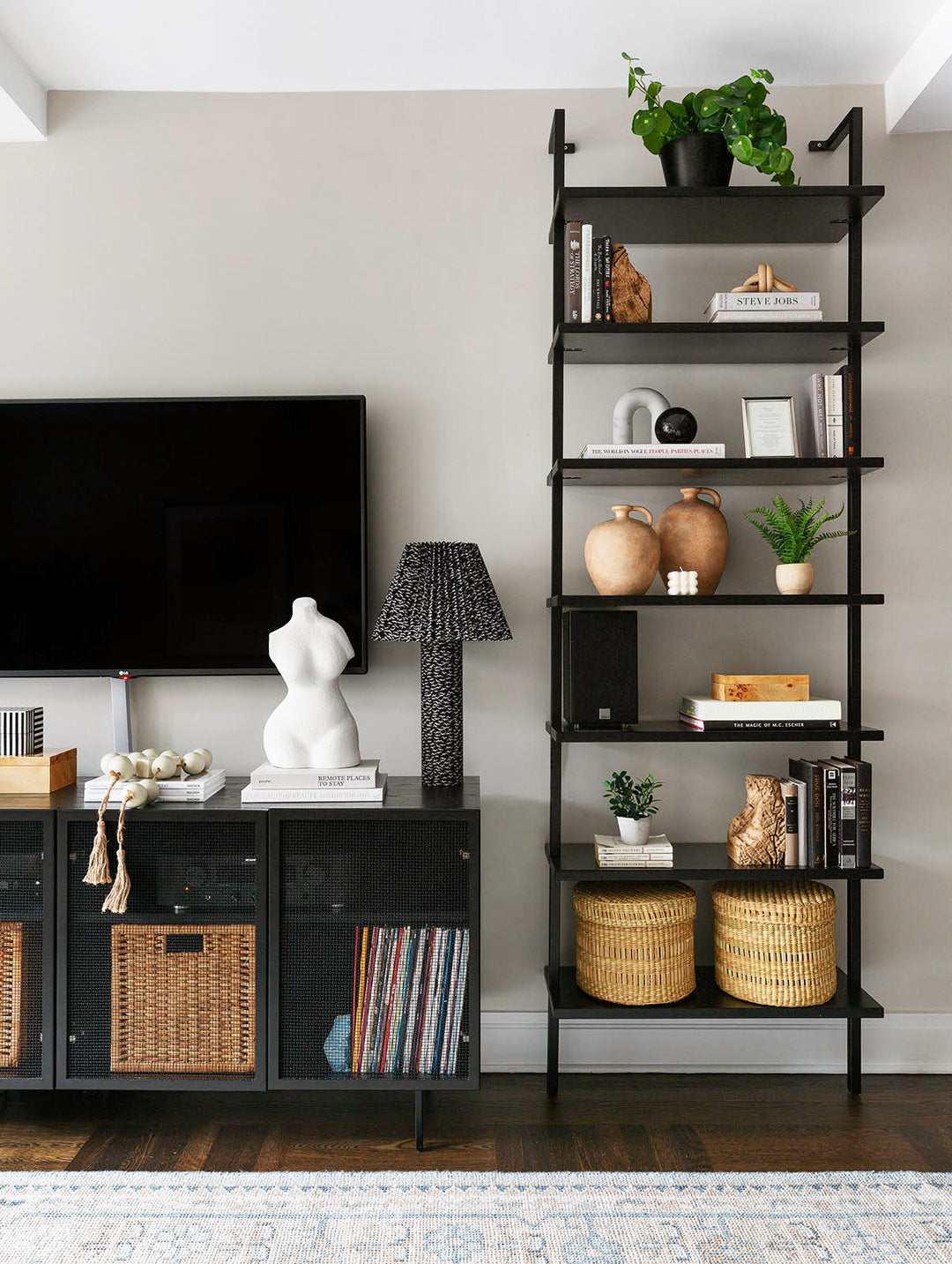 Dark woods and black framed shelving stand out against the Classic light beige painted walls in this living room with a neutral color palette.