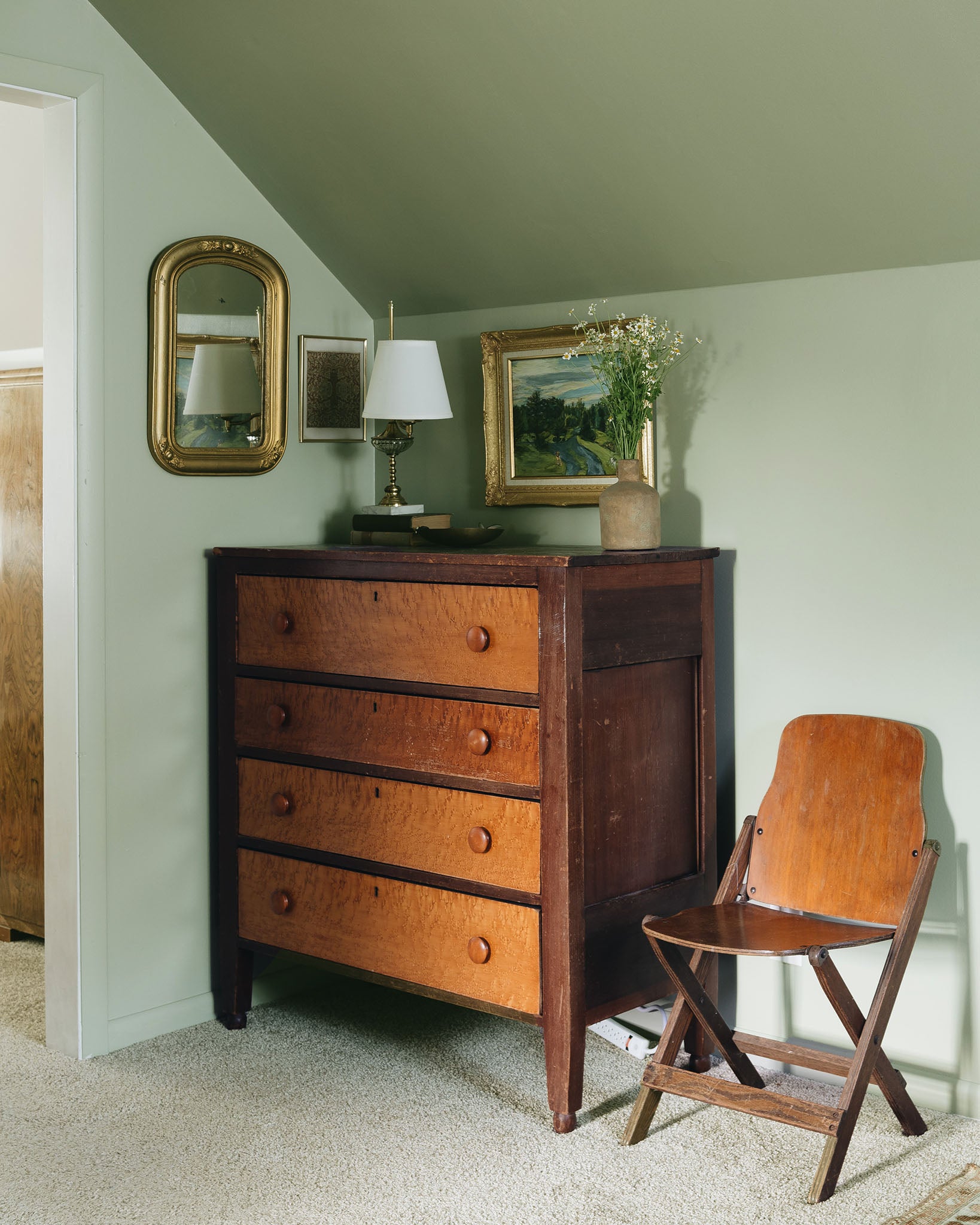 This cottagecore bedroom pairs a soft green on the walls (Dirty Martini from Clare) with warm wood tones.