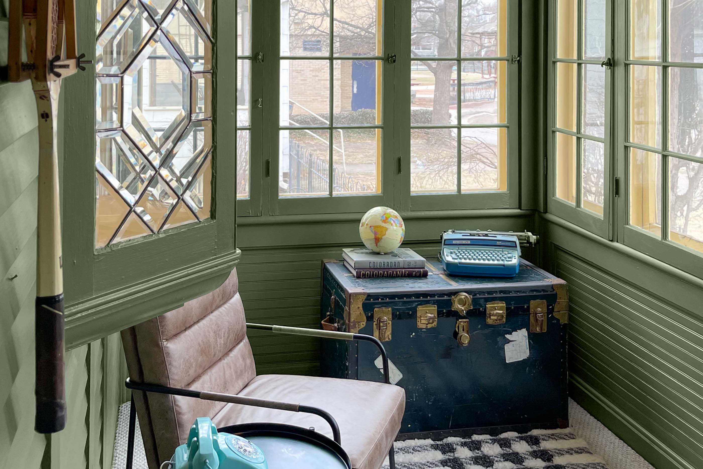 The paint color Daily Greens from Clare plays so well with the natural light in this sunroom.