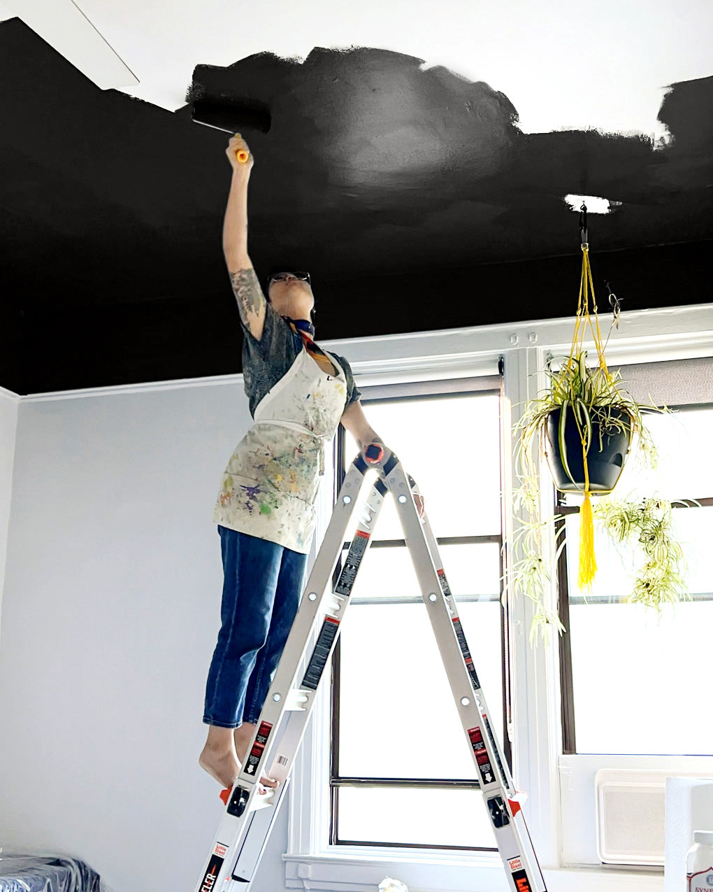 Clare Collective ambassador Lauren Hom painting the ceiling black with Blackish, a black paint color from Clare. Check out this personality-filled NYC bedroom on the Clare blog.