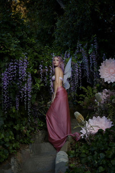 A fairy in a forest wearing the Midsummer Lilac Floating Wings