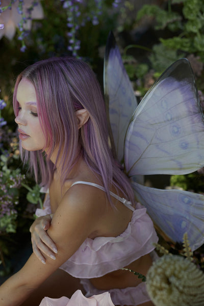 A fairy in the forest wearing the Midsummer Lilac Floating Wings