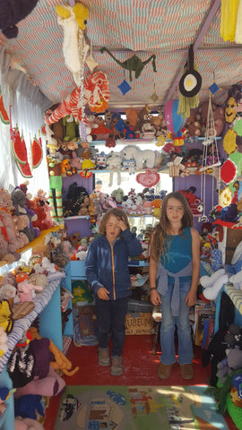 Two children standing in a small room surrounded by crocheted objects at the Crochet Museum in Joshua Tree
