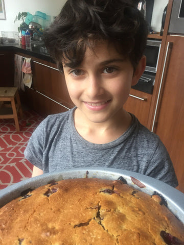 Child holding a cake with a smile on his face and tired eyes