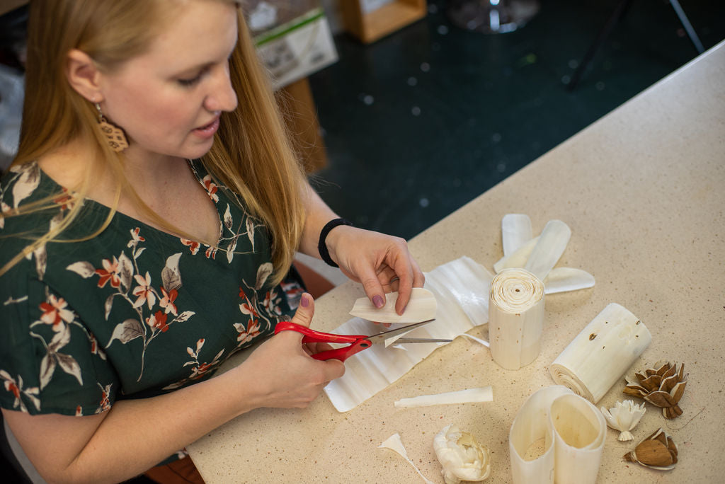 north wood blooms llc owner andi cuts sola wood rolls by hand to create a handmade sola wood flower in the wood flower design studio