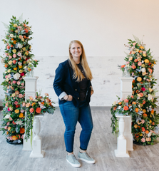 Andi Gretzinger in front of a luxury wood flower arch focal piece for a wood flower wedding photoshoot