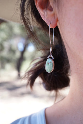 image of a single dangling turquoise earring as worn in a woman's ear