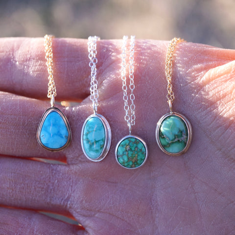 four turquoise necklaces draped over a hand.