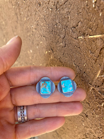 picture of a hand holding a pair of turquoise stud earrings